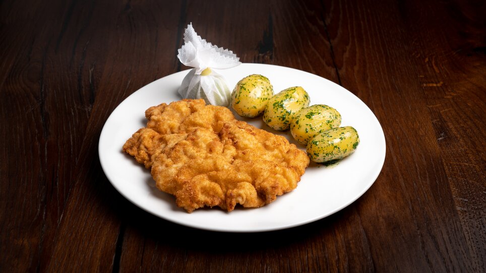 A plate with breaded schnitzel and herb potatoes. | © Mohrenwirt