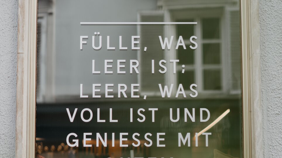 Sign with the phrase: "Fülle, was leer ist. Leere, was voll ist und genieße mit gutem Gewissen."