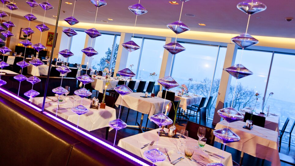 Modern restaurant view with table settings and glass installations. | © Schlossberg - Werner Krug