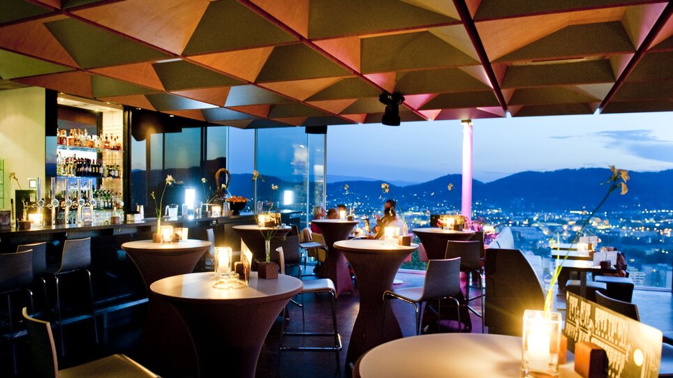 Elegant restaurant with a view of Graz, stylish interior at night. | © Schlossberg - Werner Krug