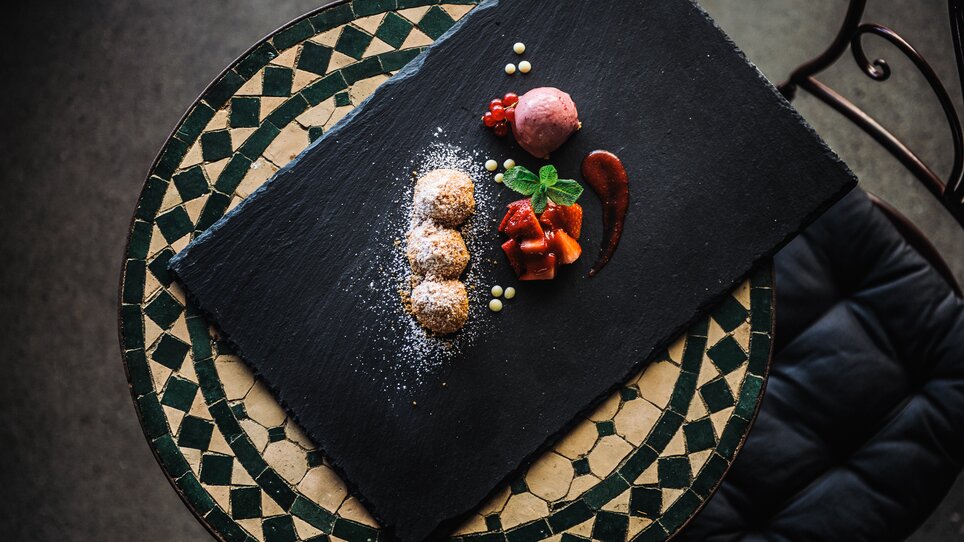 Delicious dessert on a black plate with fruit and ice cream. | © aiola - Joel Kernasenko