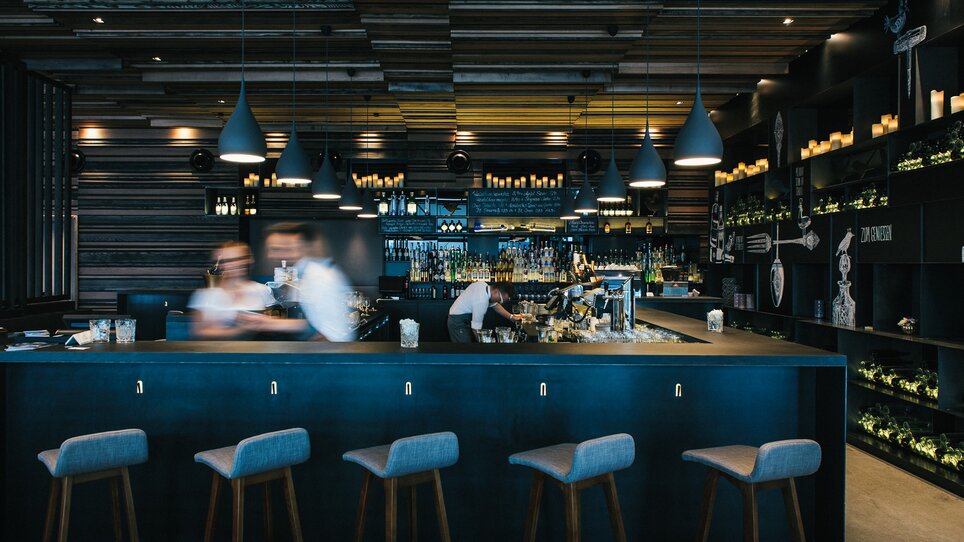 Modern bar in Graz featuring stylish wood decor and drinks. | © aiola - Joel Kernasenko