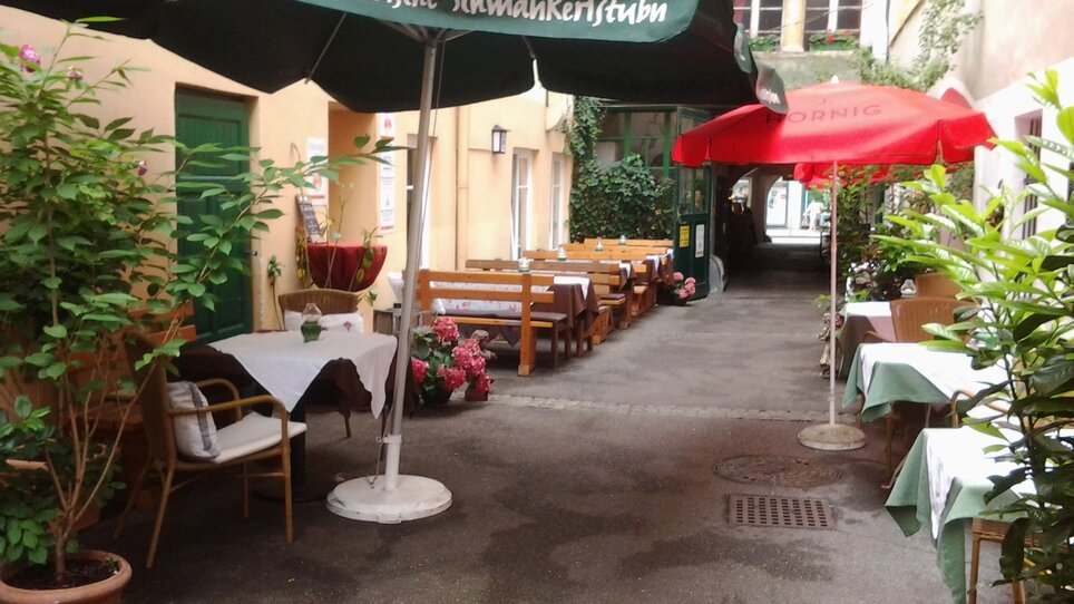 Cortile accogliente con tavoli e ombrelloni a Graz. | © Altsteirische Schmankerstube