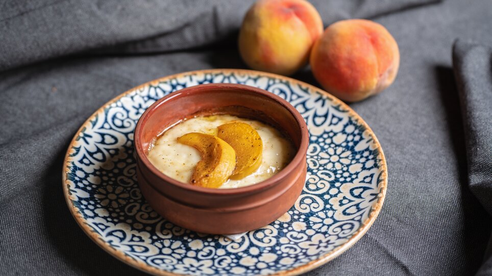 Una ciotola di dessert cremoso guarnito con fette di pesca. | © Muamer Gazibegovic
