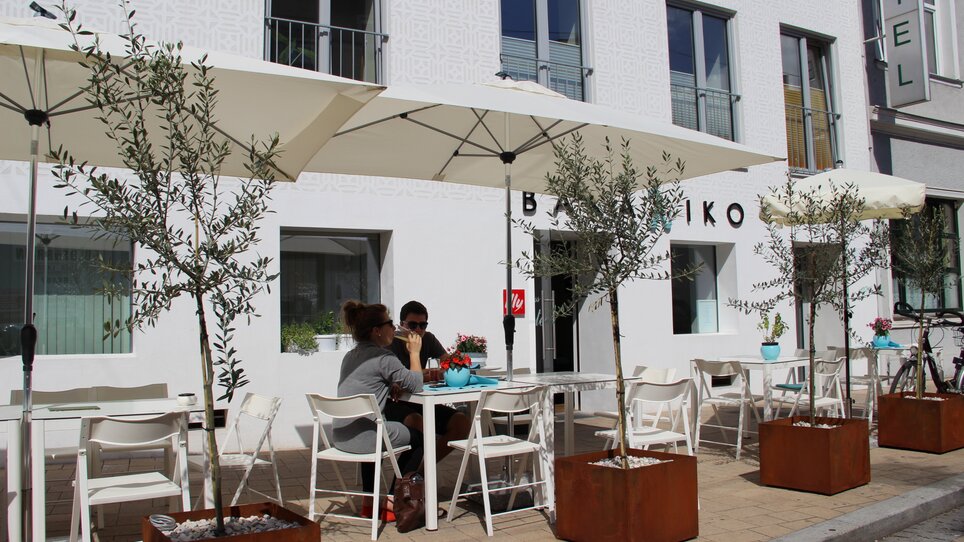 Area all'aperto di un ristorante con ulivi e ombrelloni a Graz. | © Bakaliko