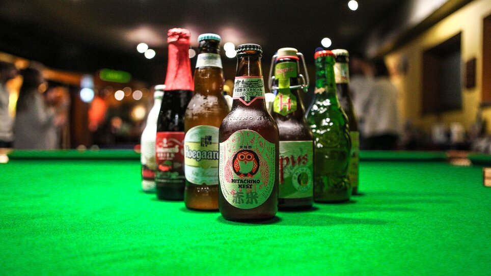 Verschiedene Bierflaschen auf einem grünen Tisch in einer Bar. | © Brot & Spiele