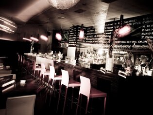 Stylische Bar mit beleuchteten Regalen und stimmungsvollem Ambiente. | © Cafe Glockenspiel