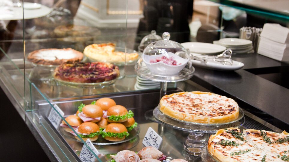 Leckereien in der Vitrine einer Bar, darunter Kuchen und Croissants. | © Tageskaffee Freiblick 