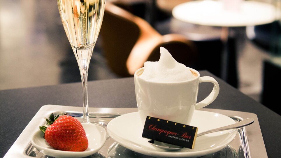 Ein Tablett mit Champagner, Kaffee und Erdbeere in einer eleganten Bar. | © Tageskaffee Freiblick 