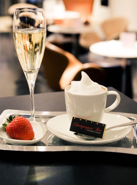 Ein Tablett mit Champagner, Kaffee und Erdbeere in einer eleganten Bar. | © Tageskaffee Freiblick 