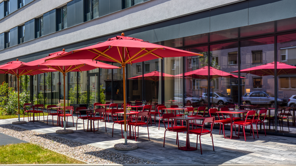 Terrasse mit roten Sonnenschirmen und Stühlen im IntercityHotel Graz. | © IntercityHotel Graz