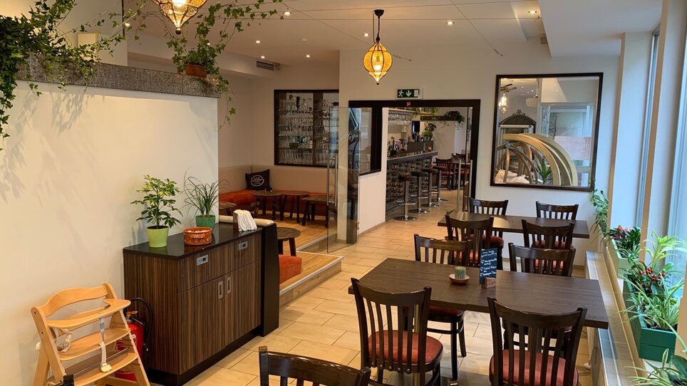 Atmosfera accogliente nel ristorante con tavoli e piante. | © R&D Gastro OG