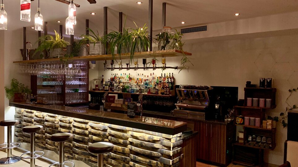 Bar moderna con una selezione di bevande e piante sullo sfondo. | © R&D Gastro OG