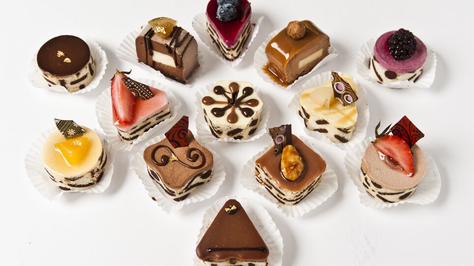 Colorful mini desserts on a white surface, artistically garnished. | © Delikatessen Frankowitsch