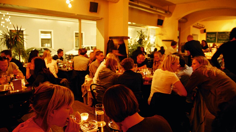 Gemütliches Restaurant mit vielen Gästen, warmem Licht und Pflanzen. | © Die Scherbe