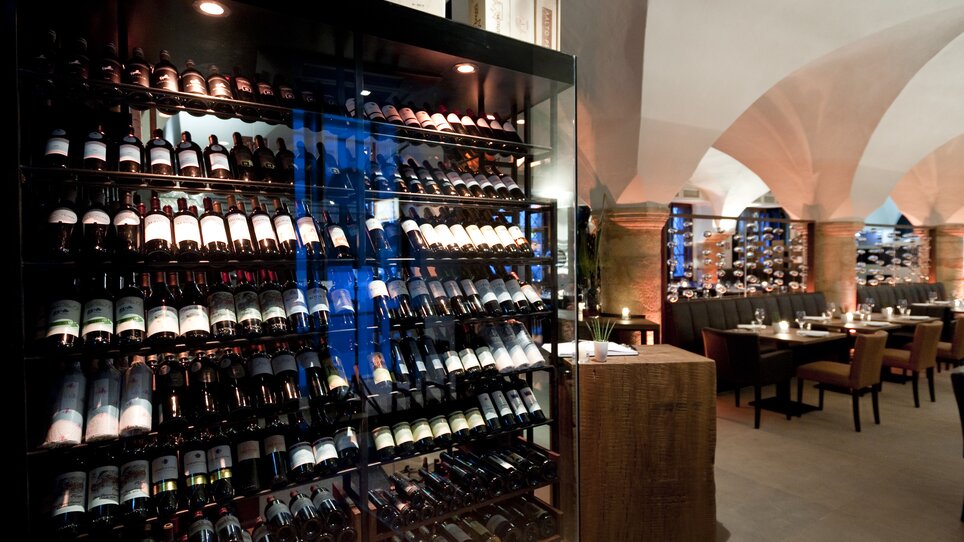 Shelf with a wide selection of wines and tables in the background. | © El Gaucho - Werner Krug