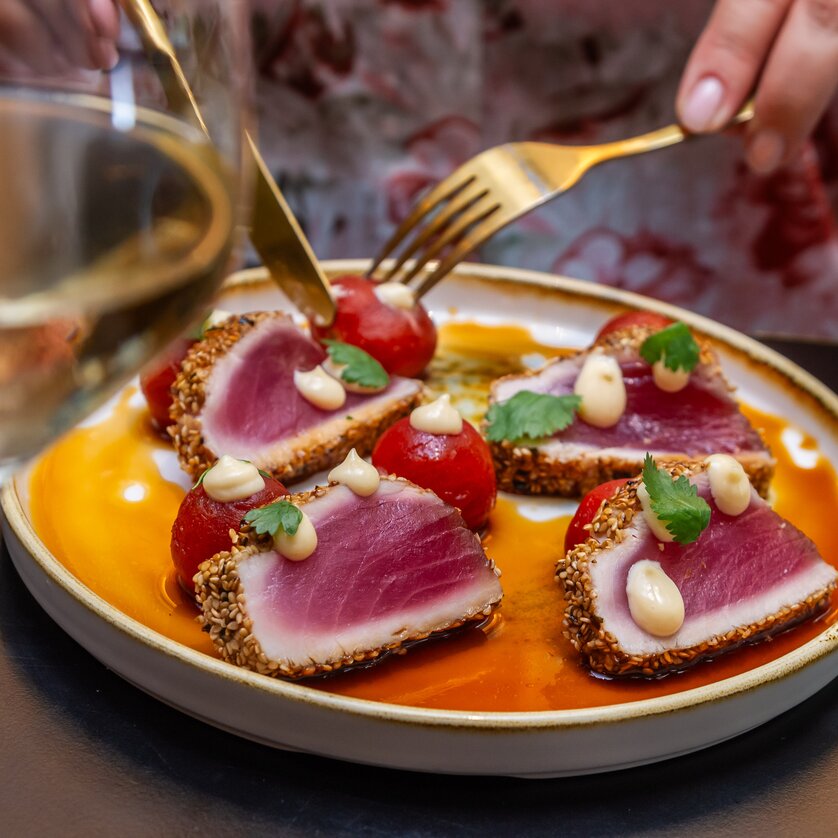 Ein Teller mit Thunfisch und Kirschtomaten, serviert mit Wein. | © Paul Stajan