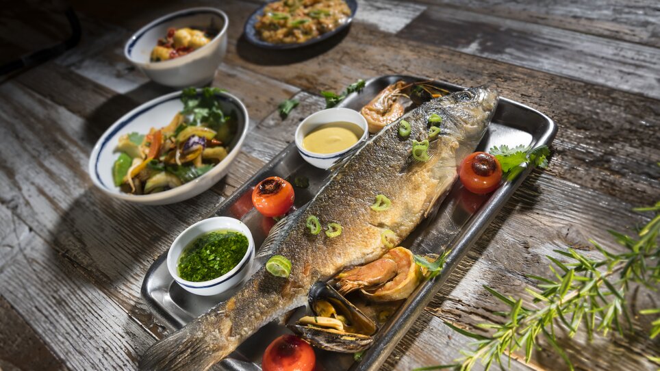 Grilled fish with shrimp and sauces served with side dishes. | © El Pescador