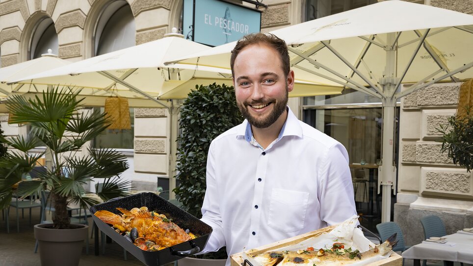 A smiling man holding seafood at a restaurant. | © El Pescador - Werner Krug