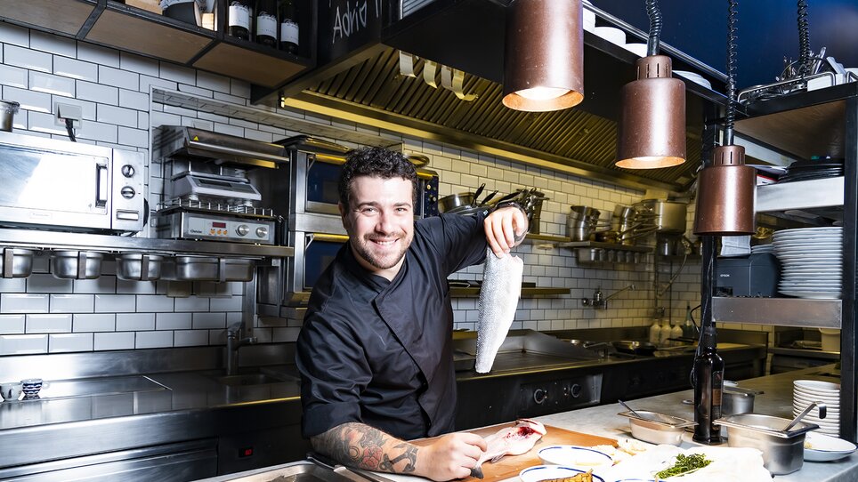 Chef holding fresh fish in a modern kitchen. | © El Pescador - Werner Krug