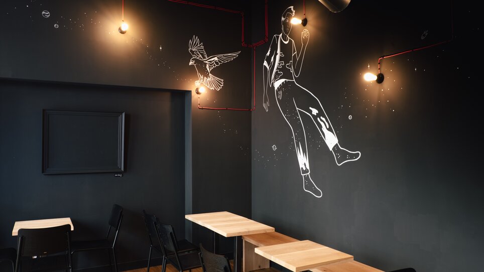 Modernes Café mit Illustrationen und stylischen Tischen. | © Leitner Daniel