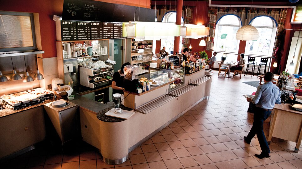 Caffè accogliente con bancone che offre cibi e bevande. | © Ginko - Udo Stelzer +