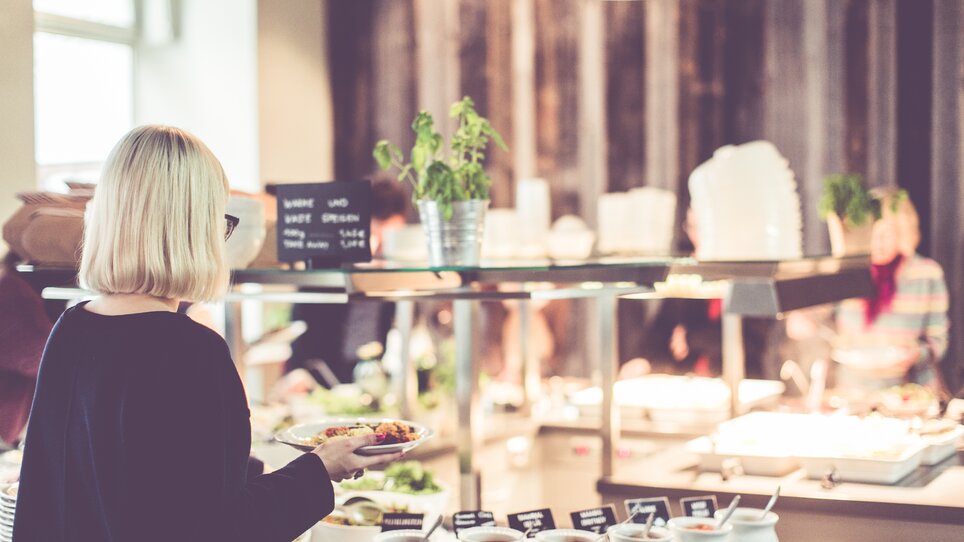 Una persona prende il cibo da un buffet. | © Lupi Spuma 