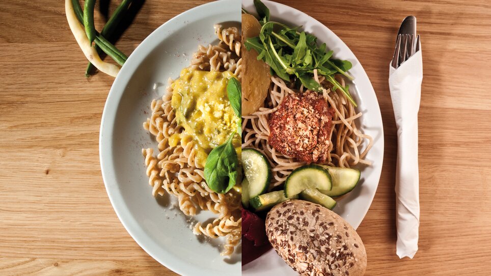 Piatto di pasta brillante con insalata e pane su una superficie in legno. | © Ginko