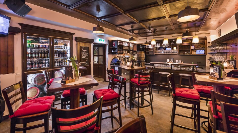 Cozy restaurant with wooden furniture and red cushions. | © Glöckl Bräu
