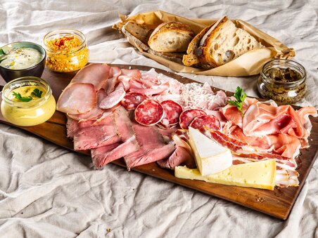 Platter with meats, cheese, dips, and bread on a table. | © Paul Stajan