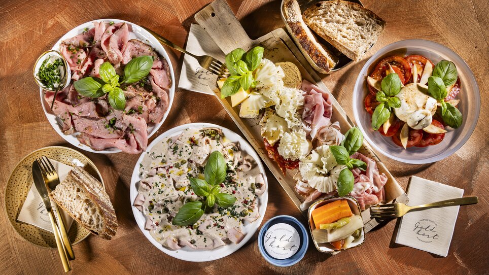 Vielfältige Speisen und Snacks auf einem Tisch, umgeben von frischem Basilikum. | © Werner Krug