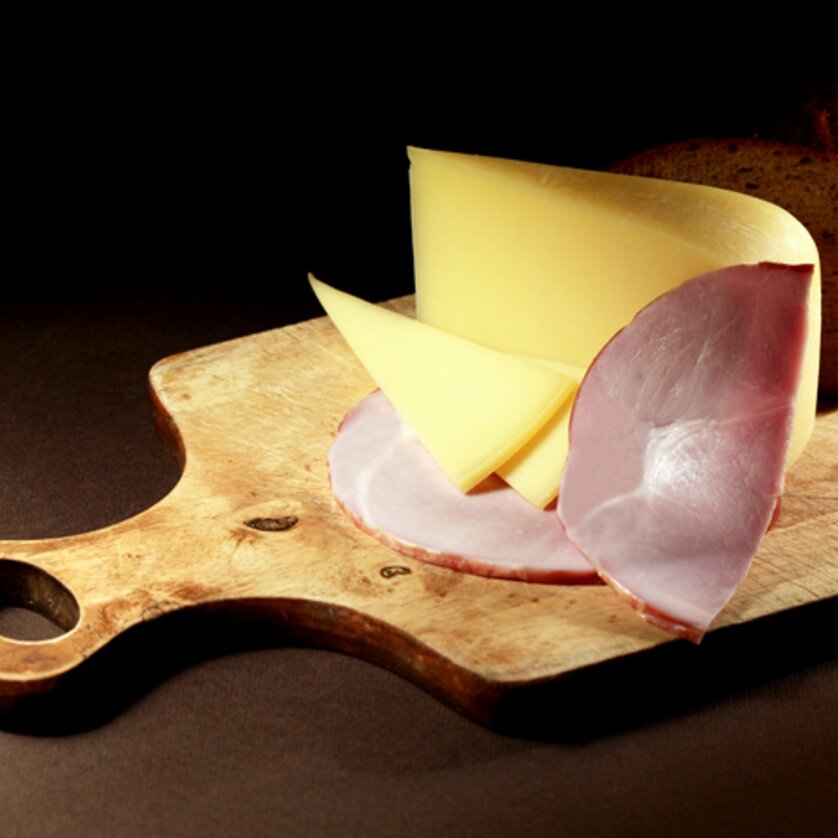 Heurigenschenke Sattler I Essen & Trinken in Graz | © Sattler Scheiben von Käse und Schinken mit einem Brot auf einem Holzbrett. | © Sattler