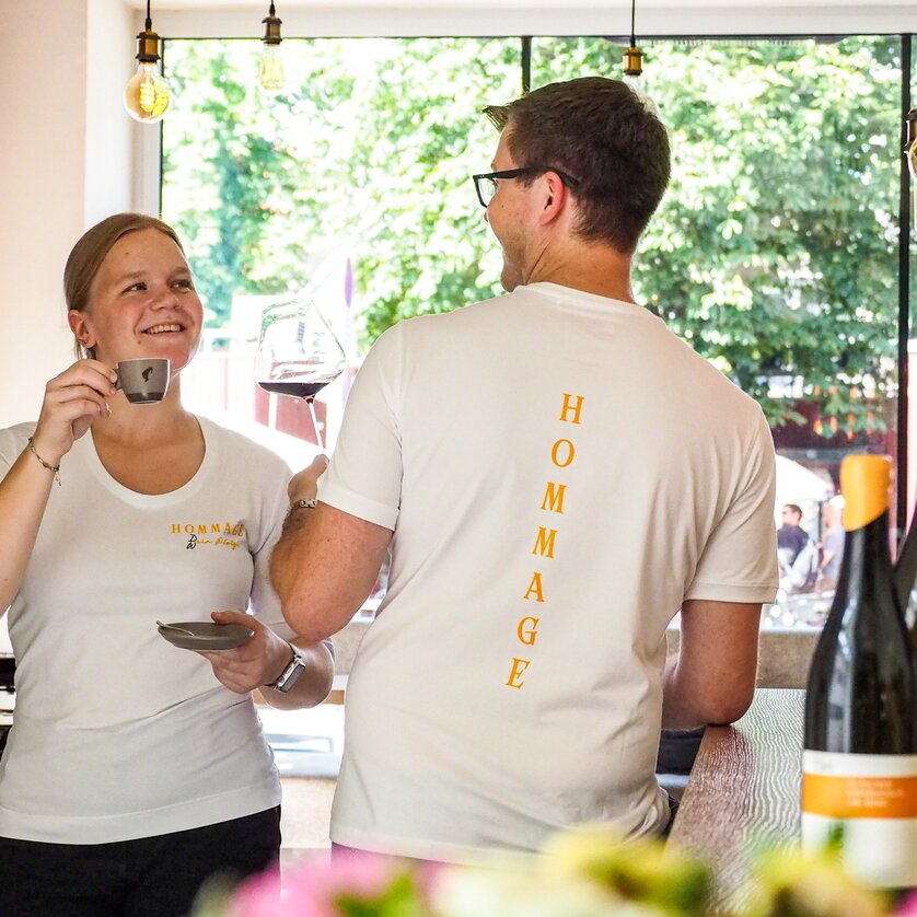 Zwei Mitarbeiter in einem Café lachen und genießen Getränke in Graz. | © Hommage