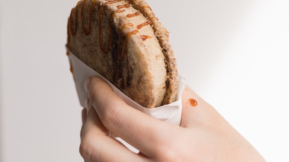 Una mano tiene un dolce con salsa di caramello. | © Kabuff