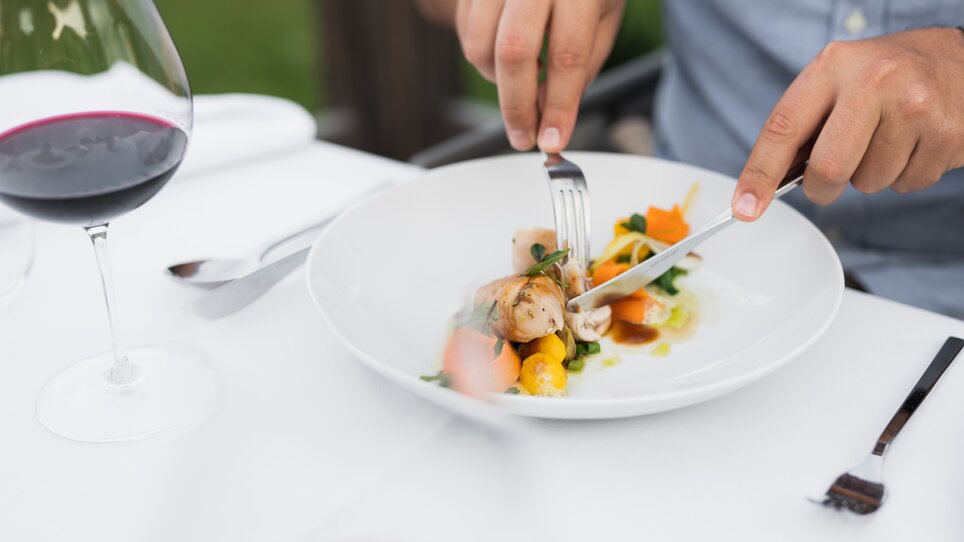Eine Person genießt ein Gericht mit Wein auf einem Tisch. | © Kehlberghof