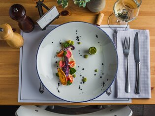 An artfully arranged plate with fresh fish and vegetables.