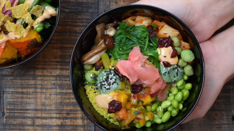 Bunte Schalen mit gesunden Bowls mit viel Gemüse auf einem Holztisch. | © Mangolds