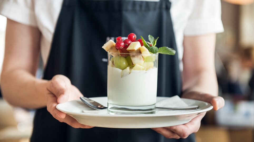 Ein Kellner serviert ein Dessert mit frischen Früchten. | © Martin Auer 