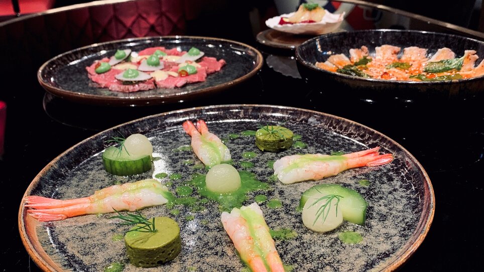 Creative dish featuring shrimp and vegetables on a black plate.