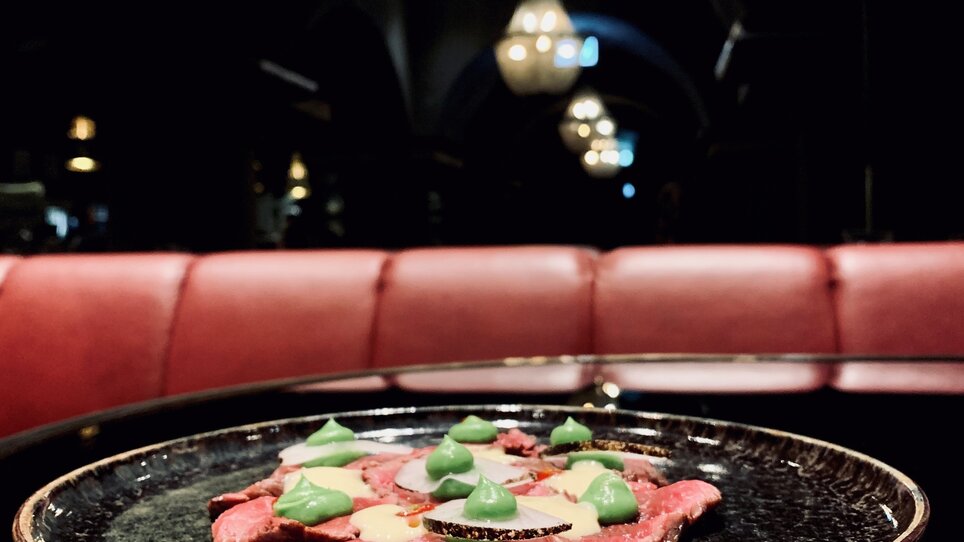 Beef carpaccio on a plate in soft lighting.