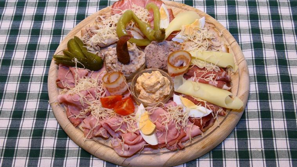 A wooden platter with assorted cold cuts and cheeses alongside toppings. | © Murheuriger