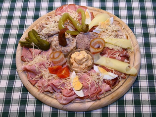A wooden platter with assorted cold cuts and cheeses alongside toppings. | © Murheuriger