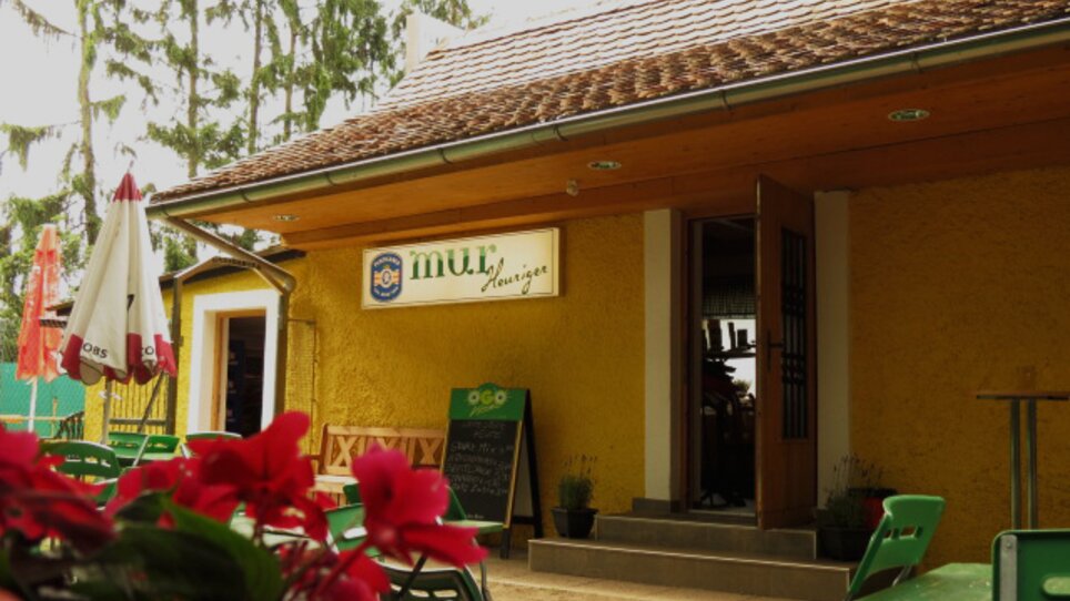 Cozy venue with yellow facade and outdoor seating, perfect for dining and drinking. | © Murheuriger