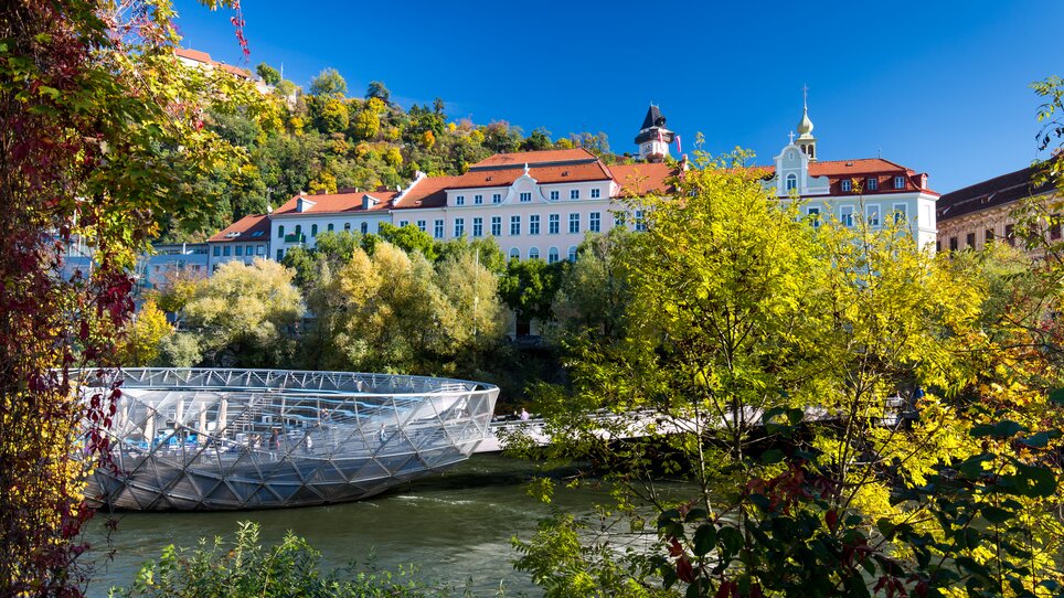 Die Murinsel in Graz mit Blick auf den Fluss Mur und die umliegenden Bäume. | © Graz Tourismus - Harry Schiffer