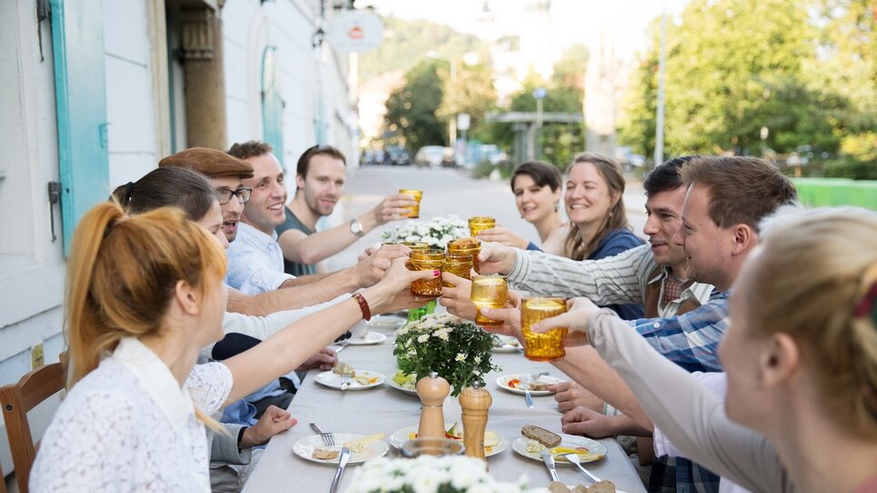Freunde stoßen mit Gläsern auf einer Terrasse in Graz an. | © Svetlana Gombats Photography 