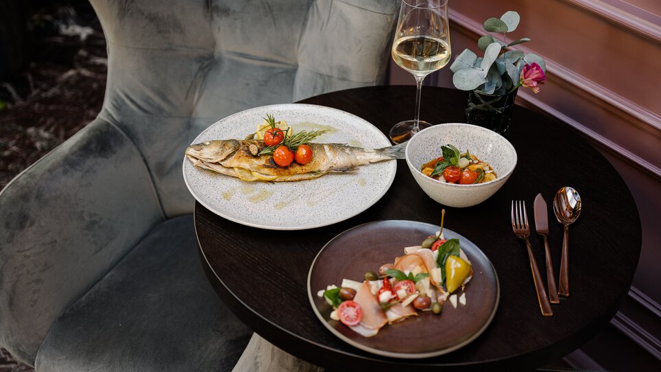 A dining table at the Operncafé with grilled fish, salad, and a glass of white wine. | © Joel Kernasenko