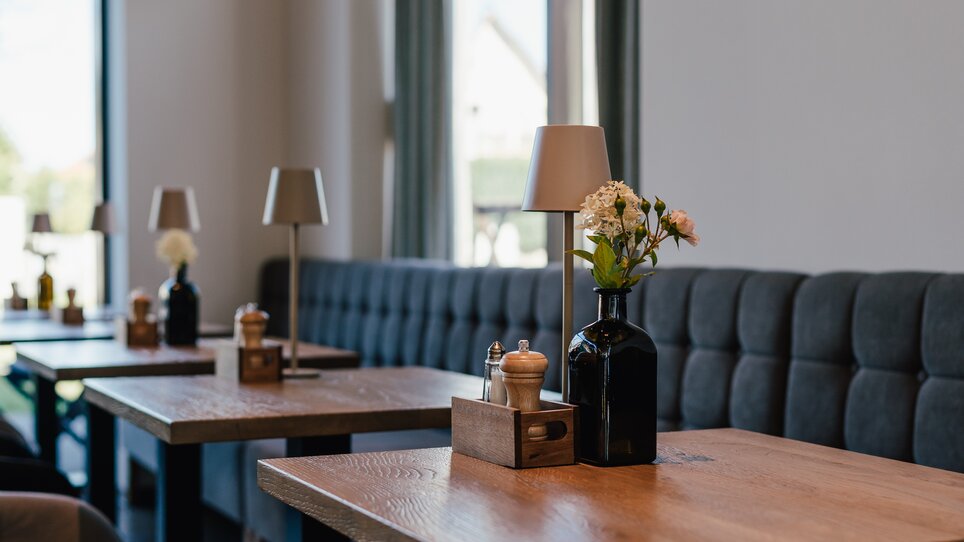 Einladende Innenansicht eines Restaurants mit Holztischen und Blumen. | © Pastaria