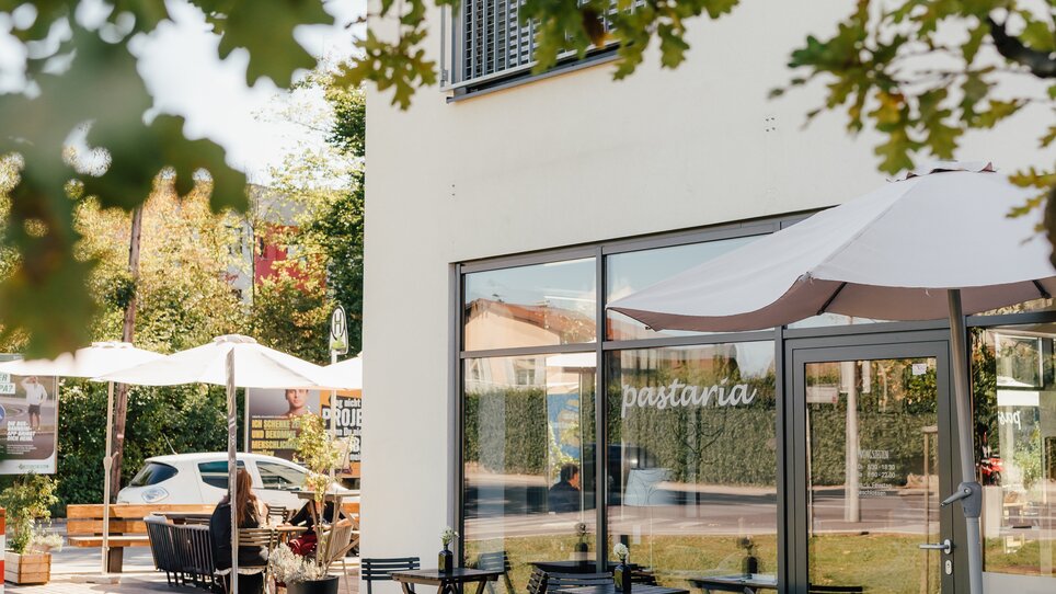 Außenansicht der Pastaria mit Tischen und Sonnenschirmen. | © Pastaria