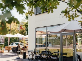 Außenansicht der Pastaria mit Tischen und Sonnenschirmen. | © Pastaria