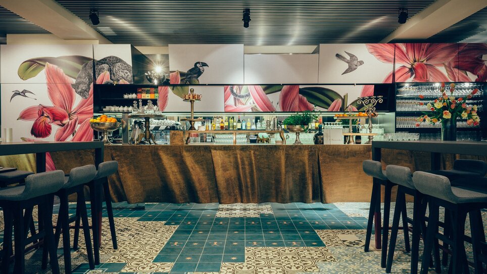 Area bar moderna con motivi floreali alle pareti e sedie eleganti. | © Promenade - Joel Kernasenko